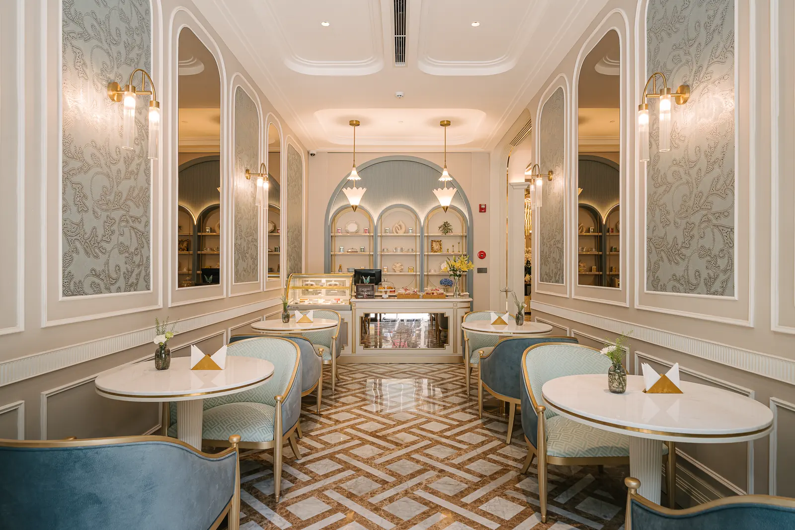 Café interior with a pastry case, marble tables and blue chairs — Crema Pastry · Classyc Hàng Buồm