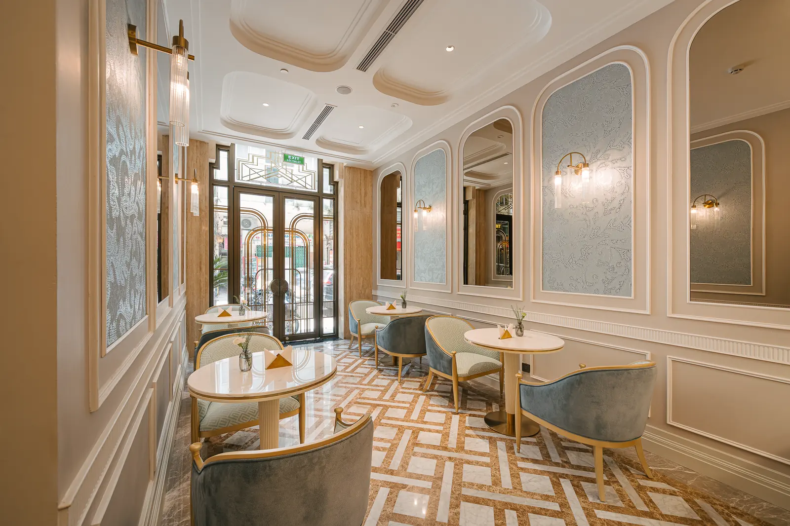 Café looking toward the street doors, with round tables and blue chairs — Crema Pastry · Classyc Hàng Buồm