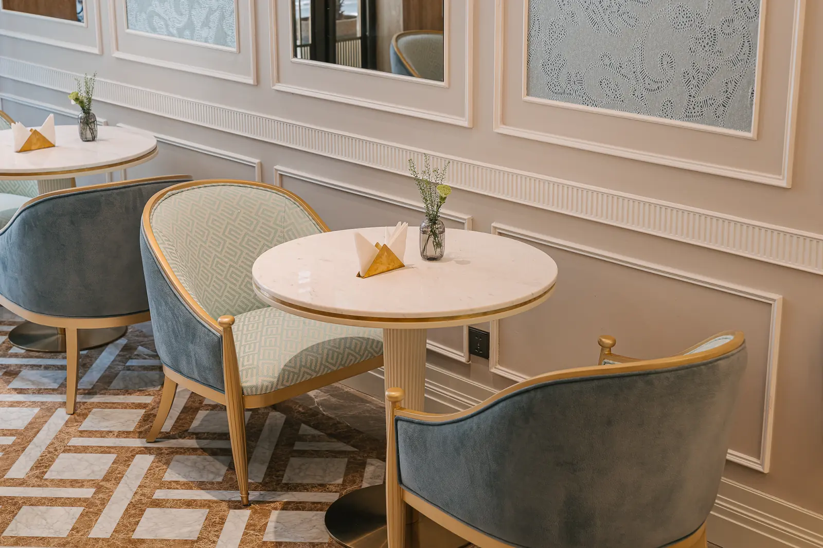 Round marble table with a gold napkin and blue chairs — Crema Pastry · Classyc Hàng Buồm