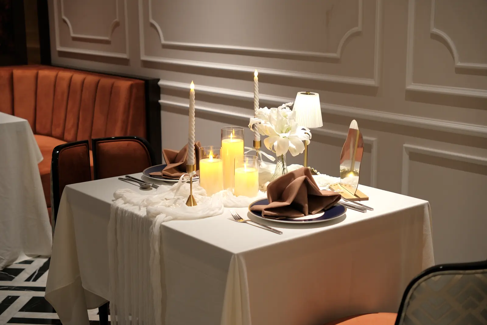 Table with white lilies, candles and a small lamp — Lumé Restaurant · Classyc Hàng Buồm