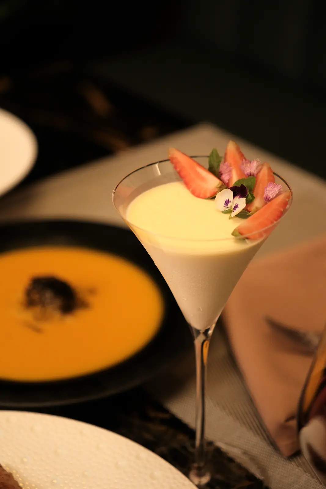 Pale cream dessert in a martini glass with strawberries — Lumé Restaurant · Classyc Hàng Buồm