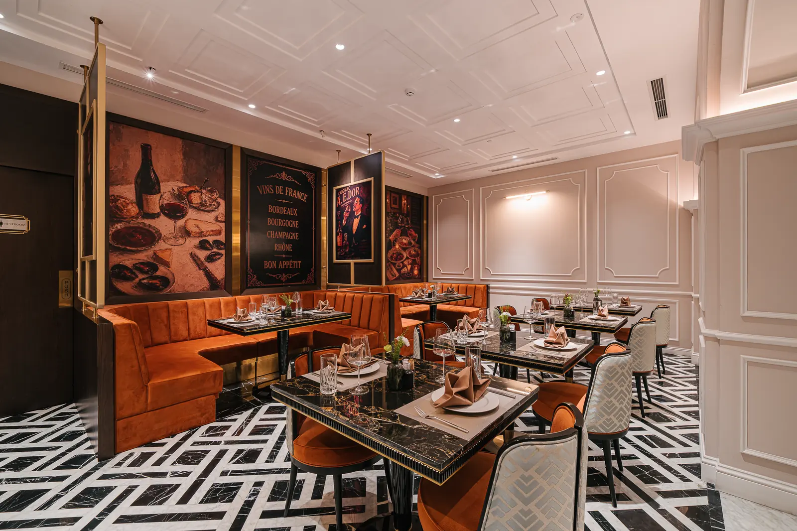 Orange banquettes and set tables beneath wine posters — Lumé Restaurant · Classyc Hàng Buồm